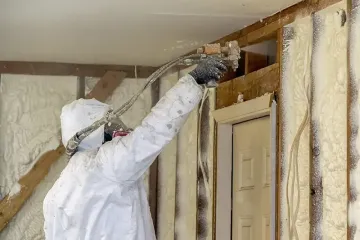 Worker spraying closed cell spray foam insulation on a home that was flooded by Hurricane Harvey